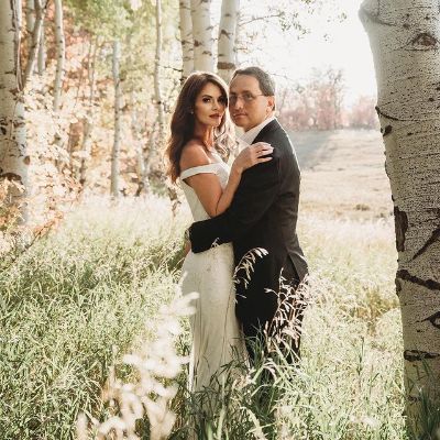 They are in the middle of a forest posing while holding each other.